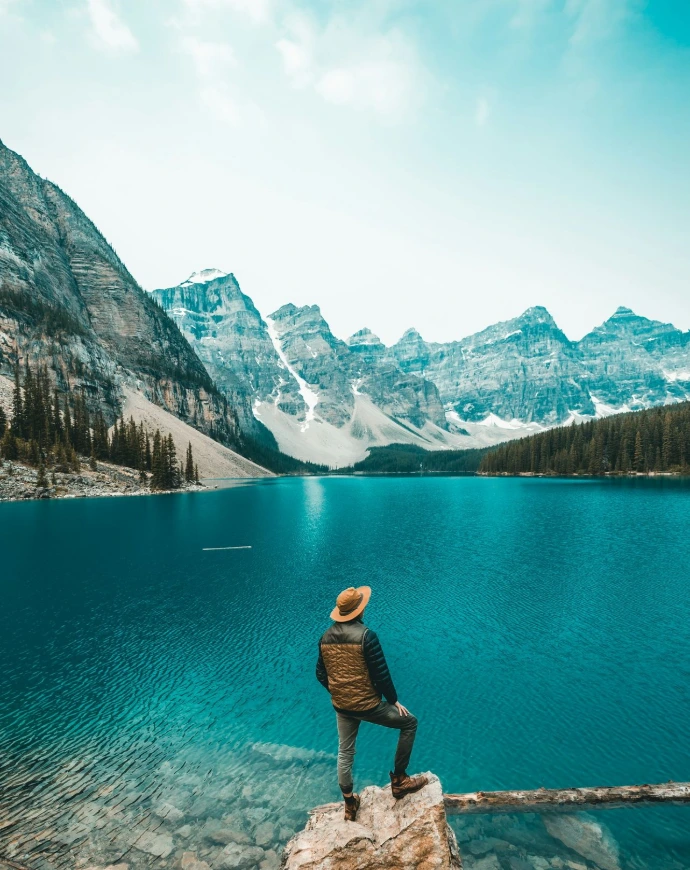 man standing on rock near lake